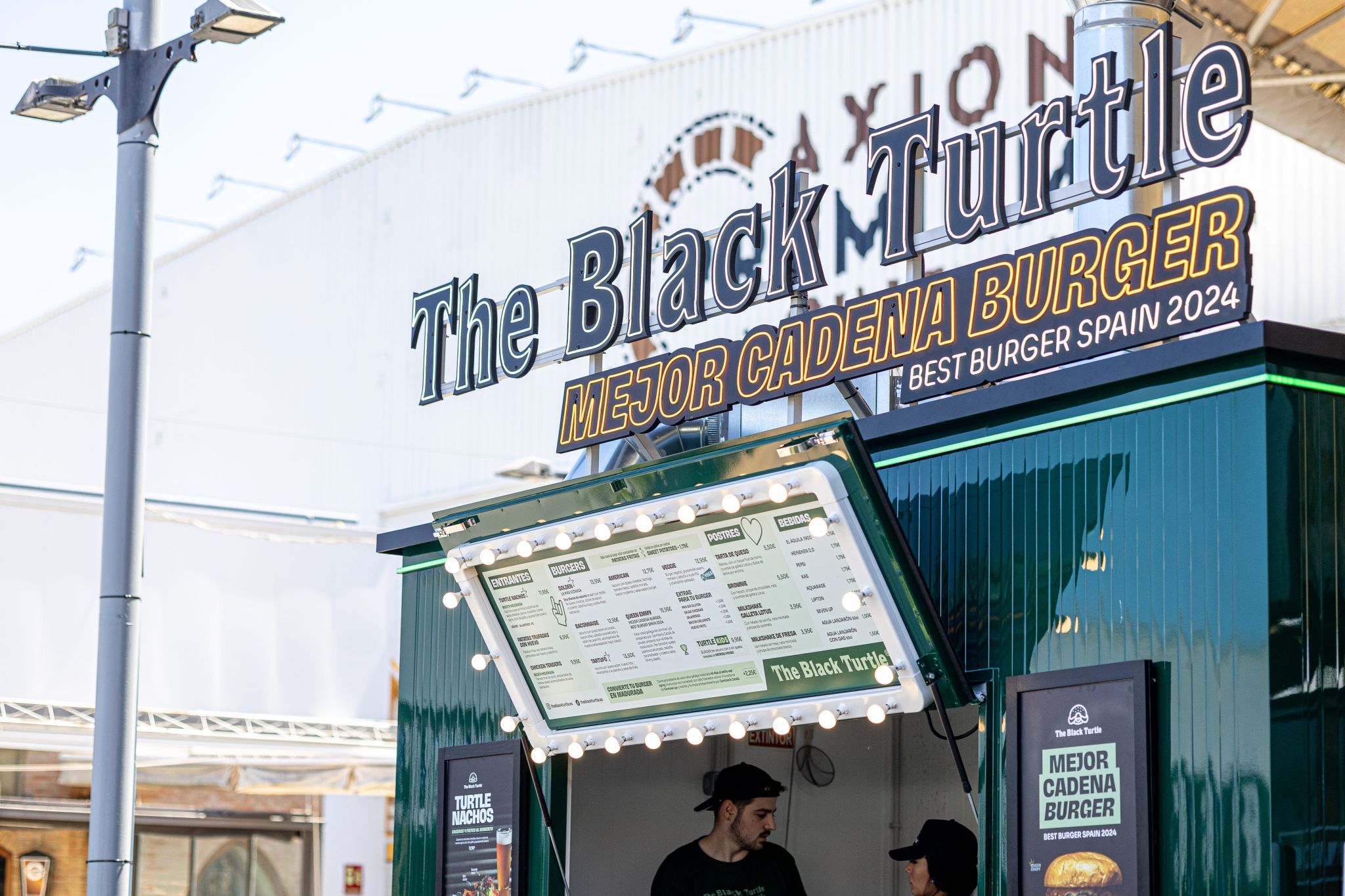 Un pequeño local con 2 empleados que pone "The Black Turtle, mejor cadena burger" (best burger spain 2024)